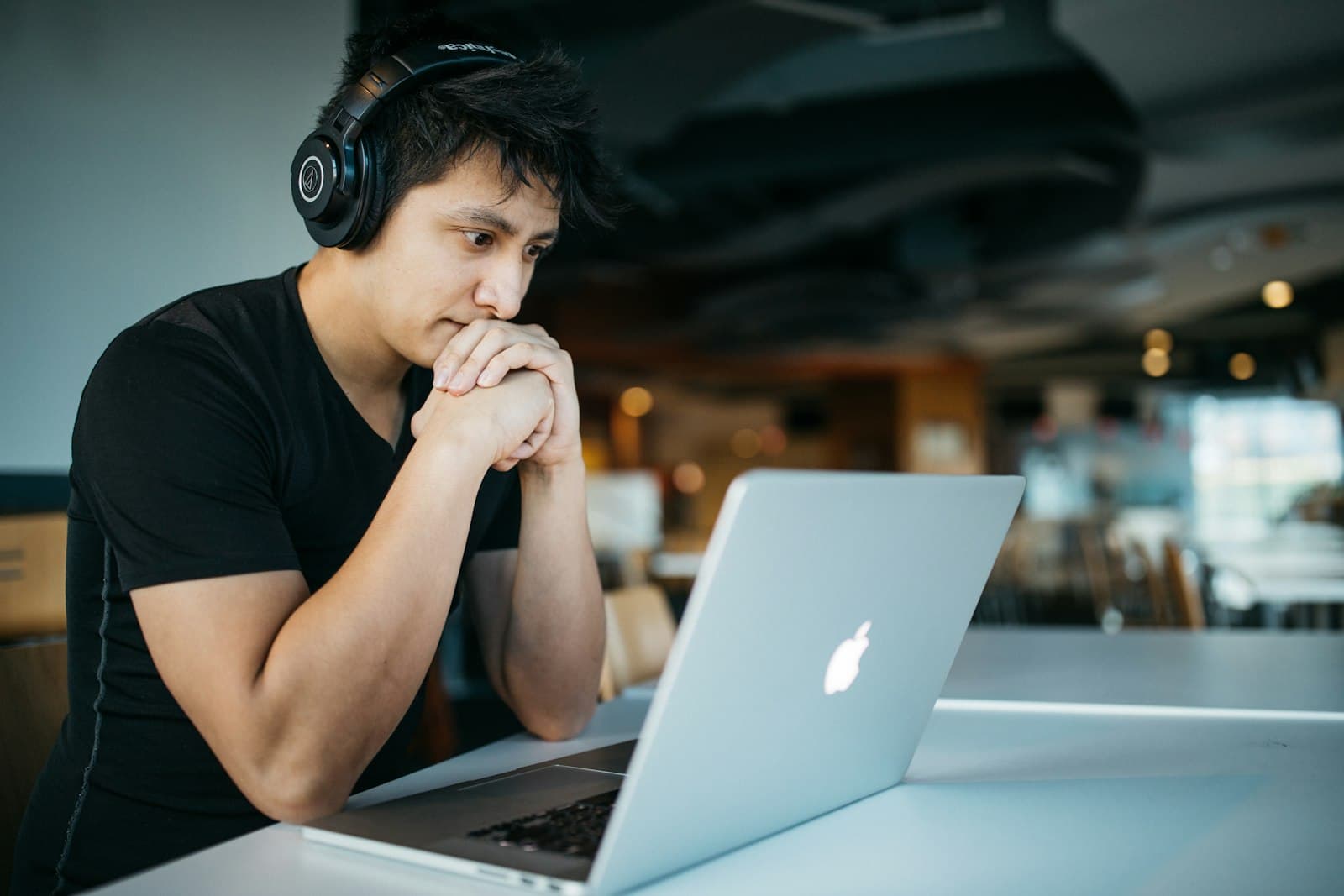 A person wearing headphones concentrating at a laptop